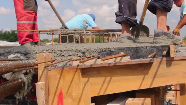 Trabajadores de la construcción están utilizando palas para alinear hormigón fresco en molde de madera con refuerzo
. - Imágenes, Vídeo