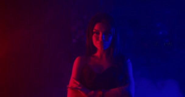 A beautiful girl is posing and looking at the camera and sexually raising her hand to her face. Shooting in blue and red neon lights. 4k - Séquence, vidéo