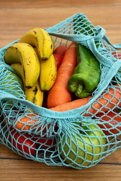 Cotton string eco bag with fruits and vegetables on wooden background - Fotoğraf, Görsel