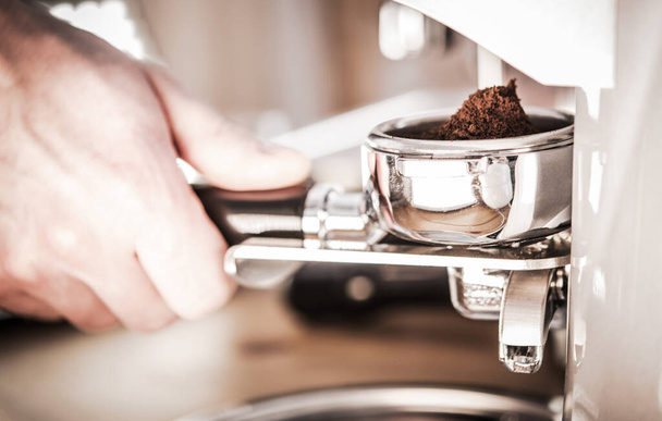 Erkek eli yakın kahve makinesinin yanında fasulye öğütüyor ve Holder 'a kahve döküyor.. - Fotoğraf, Görsel