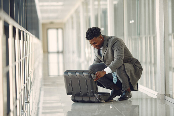 Eleganter schwarzer Mann mit Koffer am Flughafen - Foto, Bild