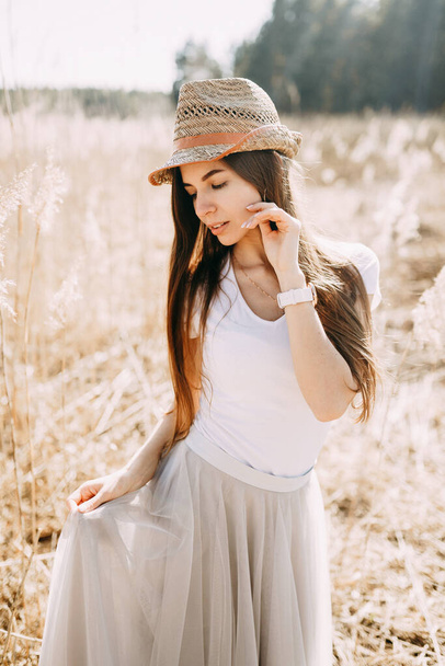 ritratto di una ragazza in un cappello di paglia per strada nell'erba alta secca
. - Foto, immagini
