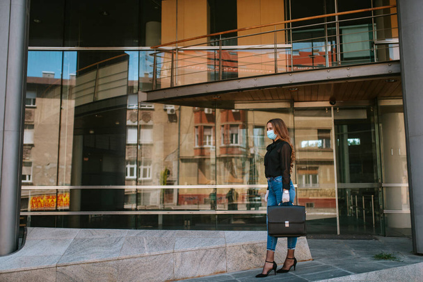 Перед компанією стоїть красива приваблива кавказька бізнес-леді з маскою і рукавичками. COVID - 19 захист від вірусів
 - Фото, зображення
