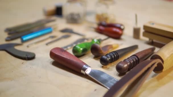 Kožené řemeslo, řemeslná řemesla, ručně vyráběné kožené nástroje s voskovou šňůrou a jehlou. Kožené kusy Pracovní plocha, pozadí tapety a texturované - Záběry, video