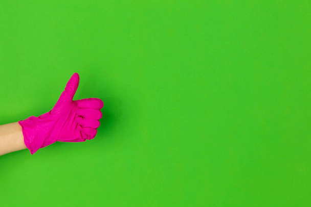 Hand in pink rubber glove showing thumb up isolated on green studio background with copyspace. - Фото, зображення
