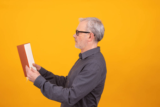 dospělý nebo starší muž s knihou izolované na barevném pozadí - Fotografie, Obrázek