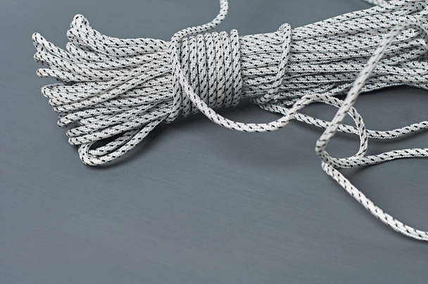 Bundle of black and white strong rope lies on dark concrete desk. Space for text - Фото, изображение