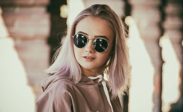 Portrait of a modern young woman with sunglasses against the background of urban brick architecture. Fashionable portrait of a girl in an urban environment. - Fotografie, Obrázek