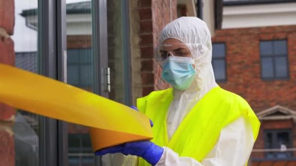healthcare worker sealing door with caution tape - Materiał filmowy, wideo