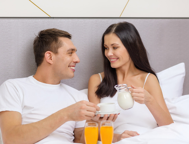 Smiling couple having breakfast in bed in hotel - Фото, изображение