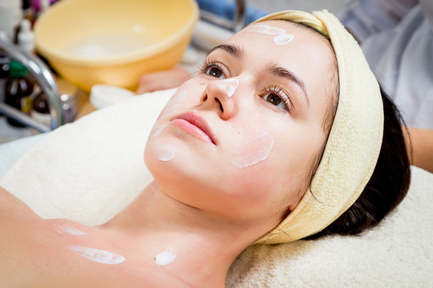 Косметолог наносит крем на лицо женщины
 - Фото, изображение