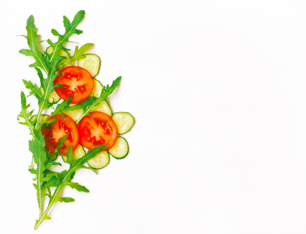 tomato, cucumber, arugula leaves, border on white background, top view, abstract bouquet - Foto, Imagen