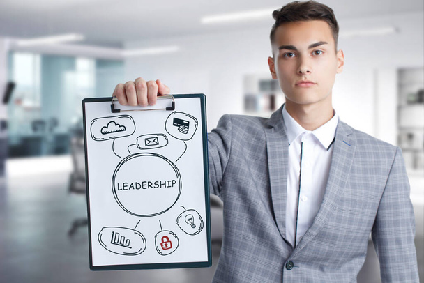 Business, Technology, Internet and network concept. Young businessman working on a virtual screen of the future and sees the inscription: Leadership - Photo, Image