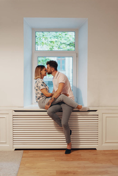 Couple in love sitting on the windowsill - Fotó, kép