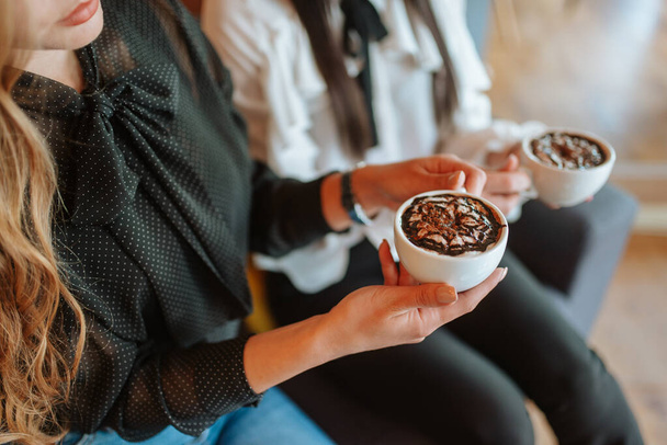 Крупним планом руки ділових жінок з чашками кави
 - Фото, зображення