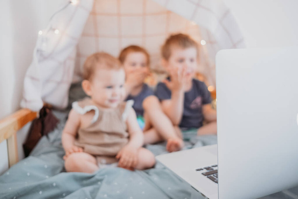 Трое детей смотрят на ноутбук, мультики, видео-чат во время карантина. время, проведенное дома во время изоляции из-за пандемии covid19
 - Фото, изображение