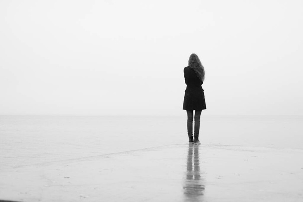 Una chica solitaria mira a la distancia bajo la lluvia. Blanco y negro. Soledad.
 - Foto, Imagen