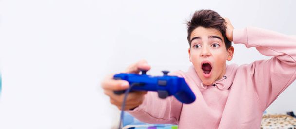 Junge mit Spielkonsole Steuerknüppel und Überraschungsausdruck isoliert auf Hintergrund mit Platz - Foto, Bild