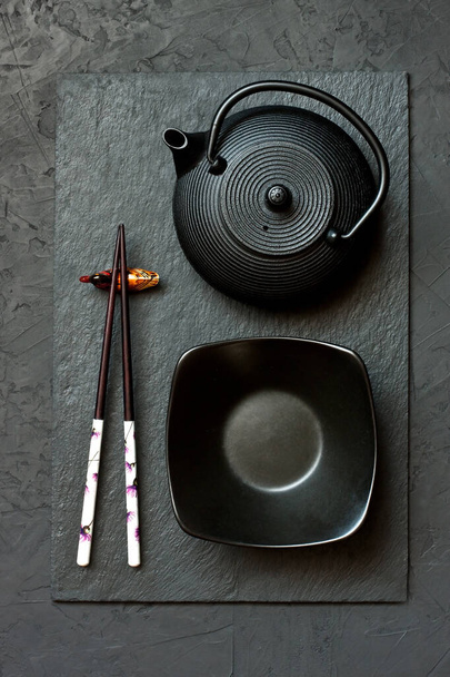 Black slate plate with chopstick on dark background. Flat lay. Asian food concept - Foto, imagen