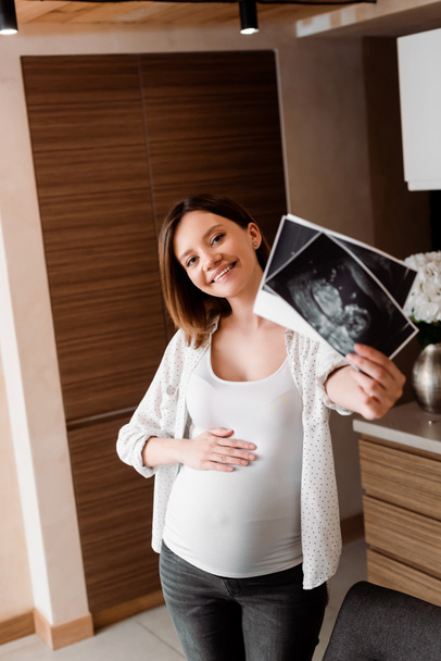 Ultrason fotoğrafları tutan mutlu ve hamile bir kadının seçici odağı.  - Fotoğraf, Görsel