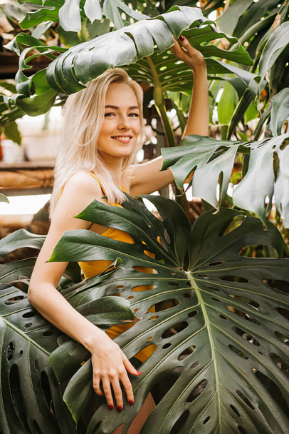 Woman in swimsuit on tropical plants background - Фото, изображение