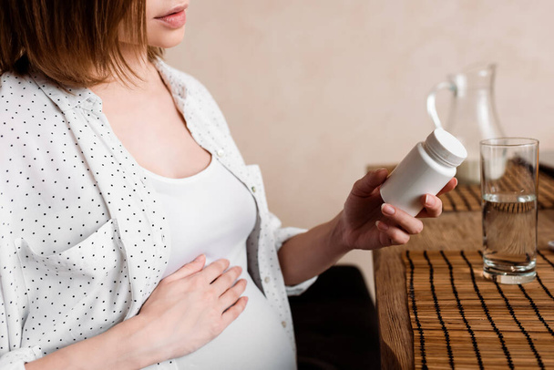 妊娠中の女性がビタミンで瓶を持ち  - 写真・画像