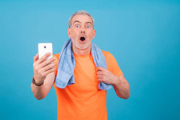 uomo adulto o anziano con abbigliamento sportivo e smartphone isolato su sfondo - Foto, immagini