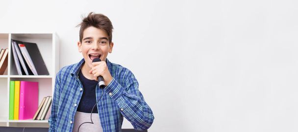 Jugendlicher Mann oder Junge mit Mikrofon singt zu Hause - Foto, Bild