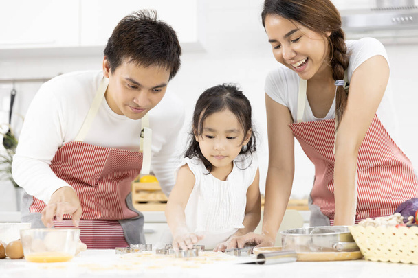 Glückliche asiatische Familienväter, Mutter und Tochter bereiten den Teig zu, backen Plätzchen in der heimischen Küche. Familie kocht Essen Konzept. - Foto, Bild