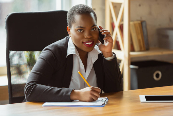 Afroamerykańska bizneswoman w stroju biurowym uśmiecha się, wygląda pewnie i szczęśliwie, odnosi sukcesy - Zdjęcie, obraz