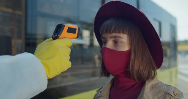 Close up shot of young female traveler having temperature checking before boarding bus. Concept of coronavirus protection and travelling. Outdoors. - Filmmaterial, Video