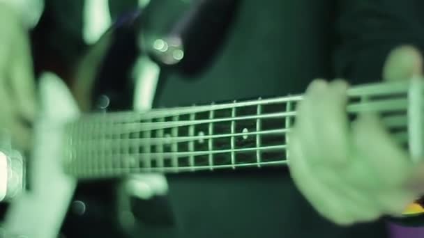 Professional young bass player playing guitar solo. The musician performs at a concert and has a good command of the instrument. Close up view of hands . Lighting colors change. - Footage, Video