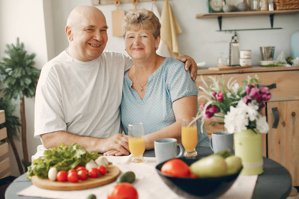 Beautiful old couple prepare food in a kitchen - Zdjęcie, obraz