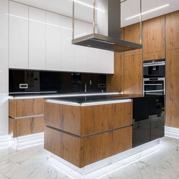 Cozinha luxuosa com piso de mármore, móveis de madeira e iluminação led moderna ativada
 - Foto, Imagem