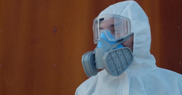 Portrait of medical worker in overall protective suit and mask turning head and looking to camera. Concept of Covid -19, pandemic and virus protection. - Video, Çekim