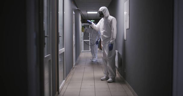 Männer in Schutzanzügen desinfizieren Gebäude - Foto, Bild