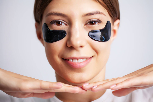 Eye patch, όμορφη γυναίκα με φυσικό μακιγιάζ και μαύρο Hydro Gel Eye Patches στο δέρμα του προσώπου - Φωτογραφία, εικόνα