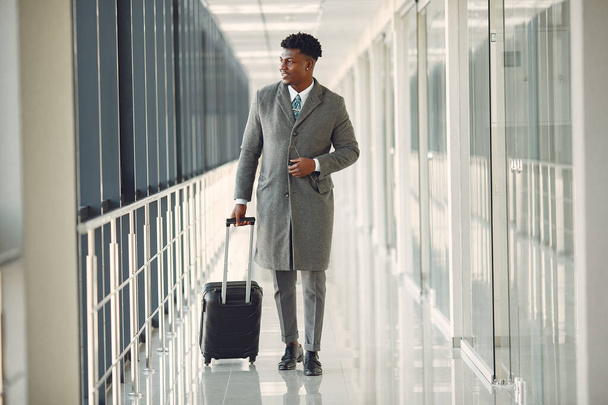 Elegant black man at the airport with a suitcase - Foto, Imagen