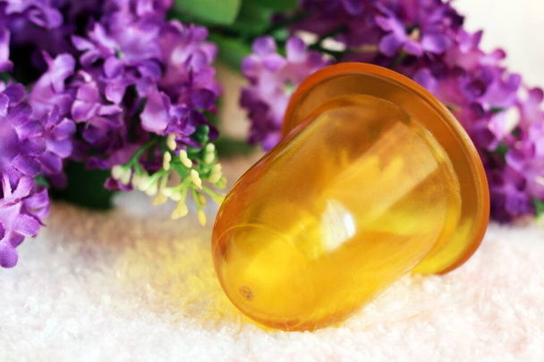 Yellow silicone massage jar and purple flowers so close - Photo, Image
