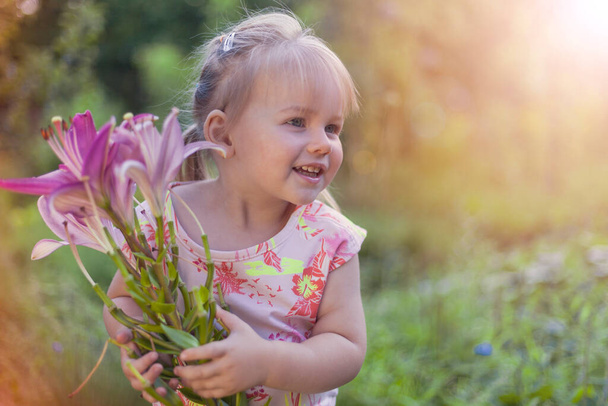 Ημέρα της Μητέρας, Όμορφο λευκό κορίτσι με ένα χαμόγελο και ένα μπουκέτο λουλούδια, η αρχή του καλοκαιριού, ένα μικρό κορίτσι δίνει λουλούδια στη μητέρα, τονισμένο  - Φωτογραφία, εικόνα