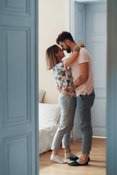 Widok profilu kochającej młodej pary przytulanie stojąc w sypialni - Zdjęcie, obraz