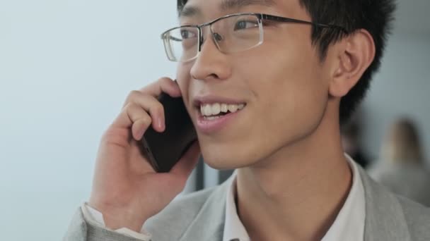 Handsome positive asian young business man indoors in office - Záběry, video