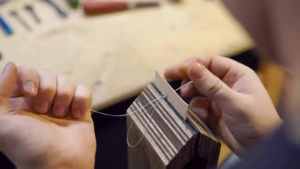 ワークショップで針縫いの革を持つ男 - 映像、動画