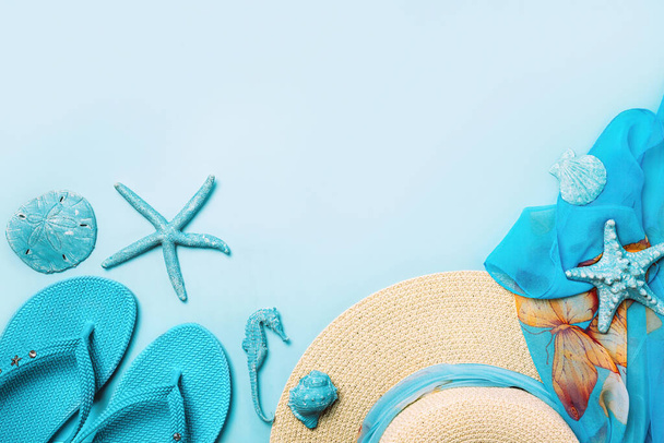 Летняя мода на синем и коралловом фоне. Синие шлепанцы, ракушки, солнцезащитные очки, бутылка и соломенная шляпа
. - Фото, изображение