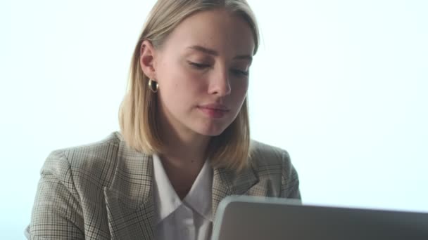 Pretty concentrated blonde young business woman indoors in office using laptop computer - Filmmaterial, Video