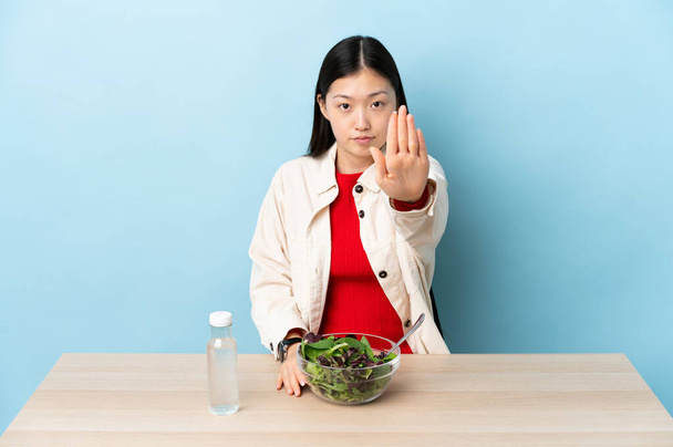 Young Chinese girl eating a salad making stop gesture - Photo, Image