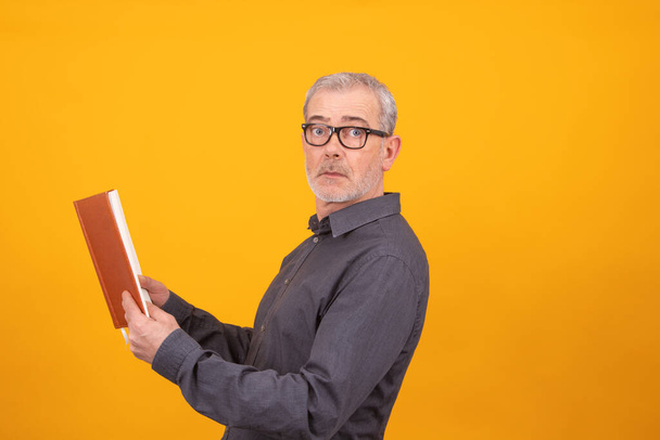 взрослый или пожилой человек с книгой изолированы на цветном фоне - Фото, изображение