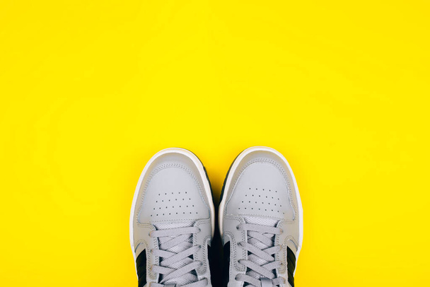 Стильні сірі кросівки на жовтому тлі
. - Фото, зображення