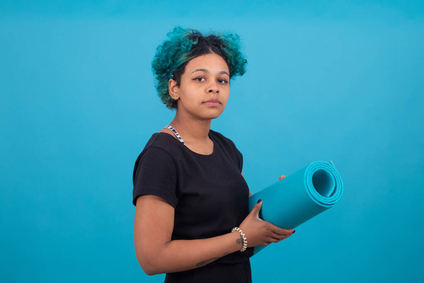 junge Frau mit Turnmatte isoliert auf farbigem Hintergrund - Foto, Bild