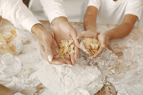 Family sitting in a kitchen and cook the dough for cookies - Foto, imagen